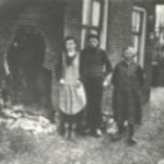 Drie personen bij het gat in de gevel van het tolhuis te Eursing nabij Beilen